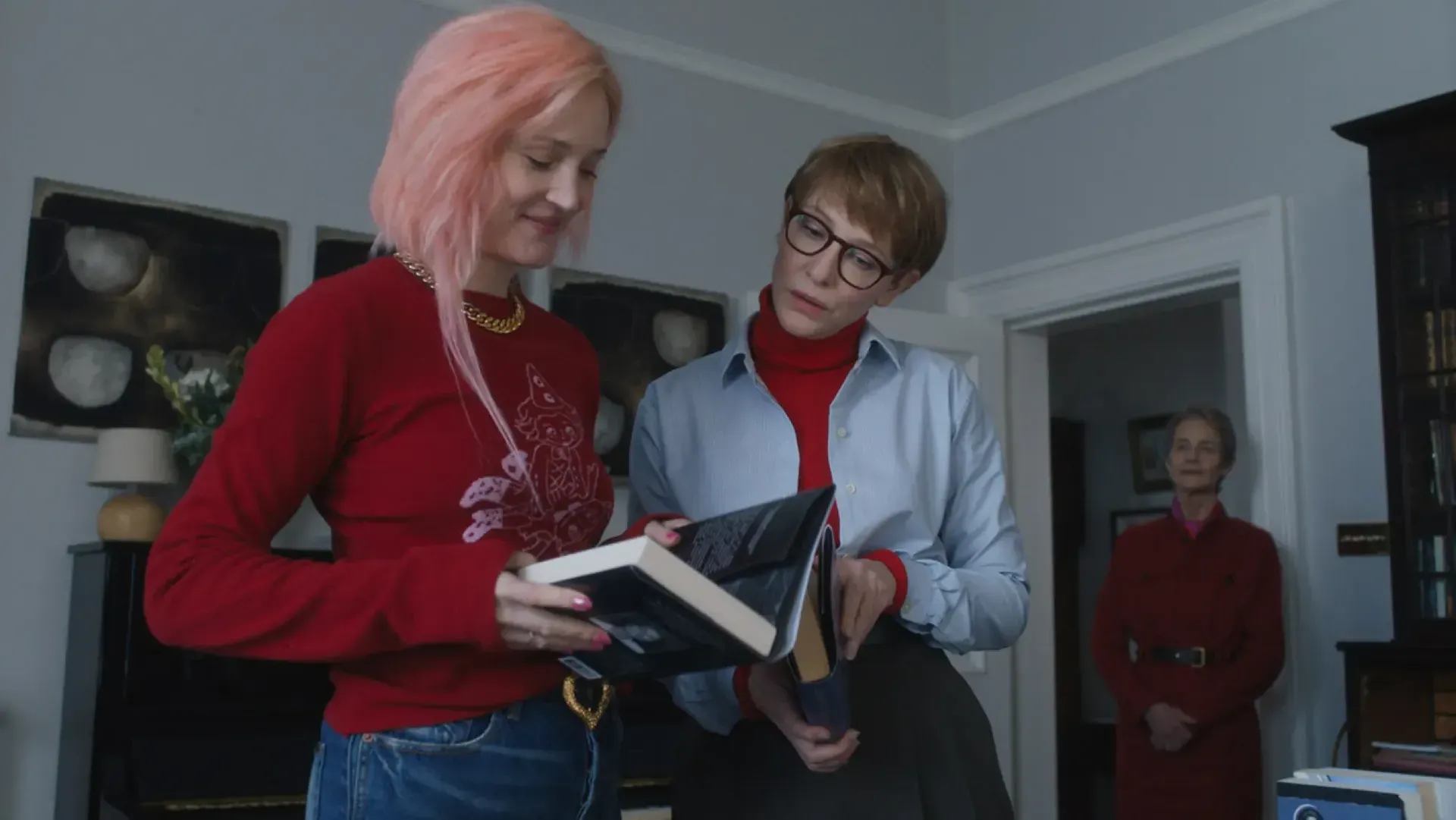 Trzy kobiety przeglądające książki w eleganckim wnętrzu.