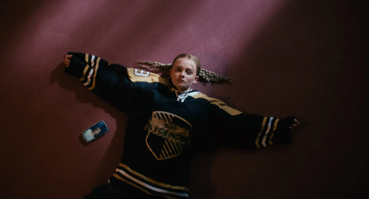 Dziewczynka leżąca z telefonem na ziemi.