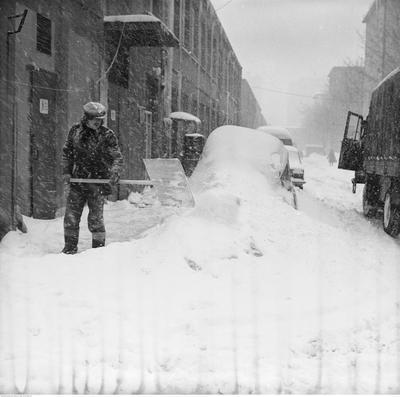 Mężczyzna z szuflą podczas odśnieżania na zapleczu pawilonów handlowych przy ul. Malczewskiego.